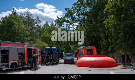 Berlin, Allemagne. 06th août 2022. Des moteurs d'incendie, un réservoir tampon et des véhicules de police se tiennent près de la scène de l'incendie. Jeudi, un incendie a éclaté à Grunewald sur le site de dynamitage de la police de Berlin. Le site de dynamitage stocke les munitions que les experts en la matière rendent normalement inoffensives. Credit: Christophe bateau/dpa/Alay Live News Banque D'Images