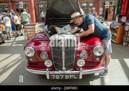 Kidderminster, Worcs, Royaume-Uni. 6th août 2022. Robert Back se réfère à son manuel de voiture original alors qu'il prépare son Daimler Conquest 1956, un projet de fierté et de joie qui a pris 10 ans de travaux de restauration, à l'Extravaganza de transport Vintage à Kidderminster, Worcestershire. L'événement annuel comprend des moteurs à vapeur ainsi que des véhicules automobiles d'époque. Crédit : Peter Lophan/Alay Live News Banque D'Images