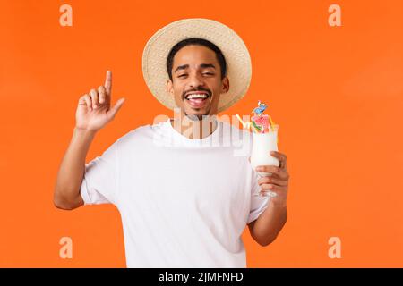 Ouais vacances rock. Joyeux et insouciant, décontracté afro-américain touriste mâle ayant le plaisir de boire de l'alcool, tenant un cocktail et Banque D'Images