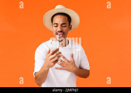 Passionné et enthousiaste, jeune homme afro-américain, parlant avec un ami en ligne, tenant un smartphone, jurant ses meilleures vacances, co Banque D'Images