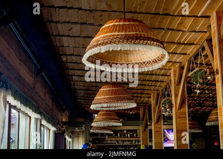 Lampes en osier, toit en bois. Décoration intérieure tendance d'un café hippster dans un style loft. Banque D'Images