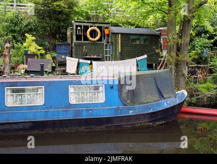 Un vieux bateau bleu et étroit amarré à côté de hangars en bois avec lavage sur la ligne sur le canal rochdale près du pont hebden Banque D'Images