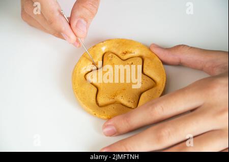 Gros plan sur les mains gratter brun sucre caramel bonbons biscuits Banque D'Images