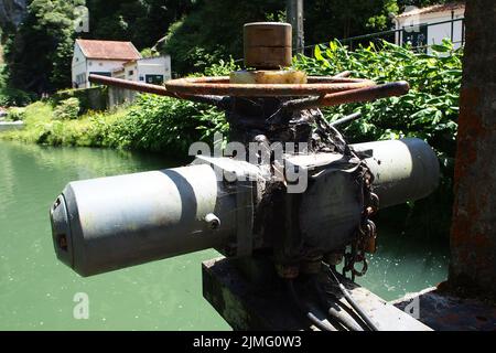 Vanne électrique rouillée, recouverte d'une toile de toile, avec une chaîne verrouillée, sur un barrage de la centrale hydroélectrique défunte Salto do Cabrito, Sao Miguel, Açores Banque D'Images