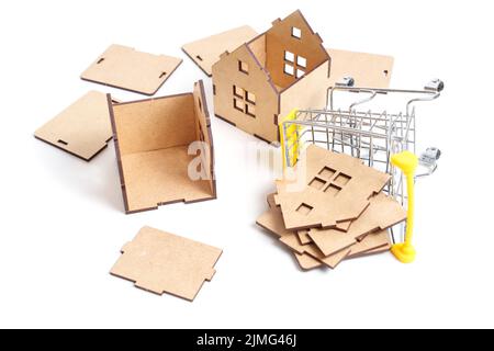 Assemblage de maisons de jouets en bois à l'aide des panneaux livrés dans un chariot miniature isolé sur blanc. Banque D'Images