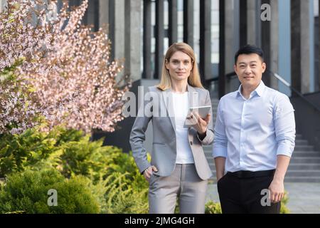 Portrait d'un groupe d'affaires diversifié, homme et femme asiatiques en costume d'affaires regardant la caméra et souriant, deux travailleurs à l'extérieur du bureau Banque D'Images