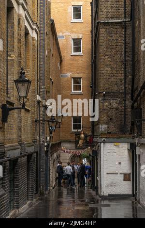 Londres, Royaume-Uni - juin 09 2022 : de jeunes britanniques boivent de la bière en face d'un bar dans une vieille rue en étant debout, Londres, Angleterre Banque D'Images