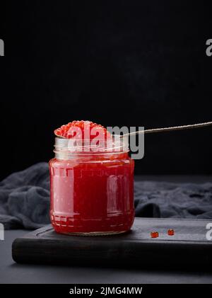 Caviar rouge granuleux frais dans un pot en verre sur une table en bois Banque D'Images