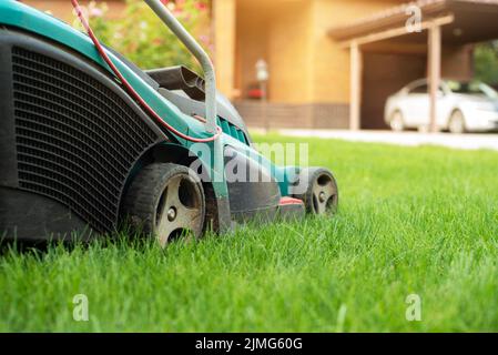 Motionnaire de pelouse sur l'herbe verte dans la maison en brique et en avant Banque D'Images