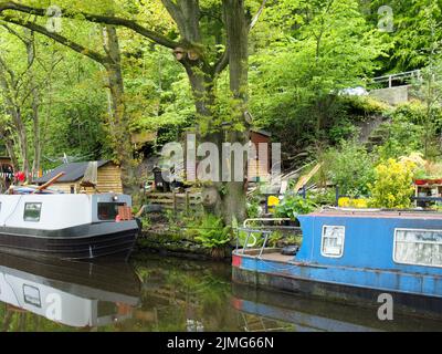 Un vieux bateau étroit amarré à côté de hangars en bois avec lavage sur la ligne sur le canal rochdale près du pont hebden Banque D'Images