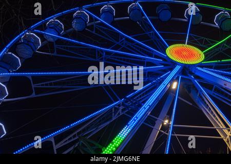 Grande roue magnifiquement éclairée la nuit à Leeds par l'hôtel de ville. Banque D'Images