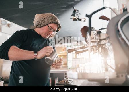 Le Barista professionnel verse du lait dans un verre de café frais pour préparer du Latte ou du cappuccino Banque D'Images