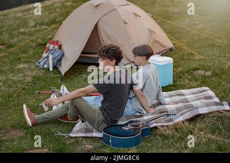 Jeune couple de touristes assis à la tente et se reposant après trekking. Randonneurs ayant le repos au camp. Banque D'Images