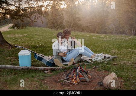 Joyeux couple de touristes assis dans le hug et rire tout en ayant pique-nique. Week-end. Banque D'Images