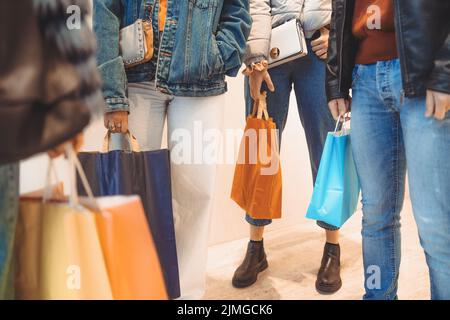 Détail des jeunes qui tiennent des sacs de shopping devant un magasin de fenêtre au centre commercial du marché - récolte - Banque D'Images