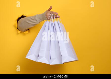 Une main féminine tient un sac jetable en papier blanc avec des poignées pour les articles d'épicerie et les vêtements. Emballage recyclable. Aucun gaspillage. Vente Banque D'Images