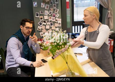 le fleuriste en présence du client recueille un bouquet de fleurs fraîches Banque D'Images