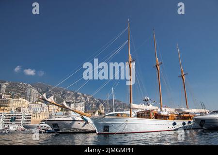 Beaucoup de yachts énormes sont dans le port de Monaco à la journée ensoleillée, Monte Carlo, la montagne est en arrière-plan, de grands mâts de voile yacht, moto Banque D'Images