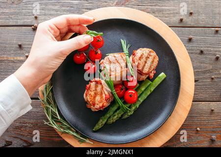 Présentation de la cuisine du restaurant. Chef décorant un plat de porc. Filets de filets grillés aux légumes Banque D'Images