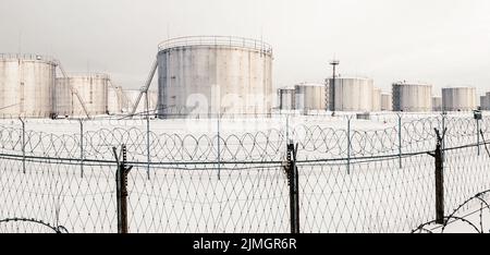 Réservoirs de stockage de gaz en hiver, ferme de réservoirs derrière une clôture recouverte de fil barbelé Banque D'Images