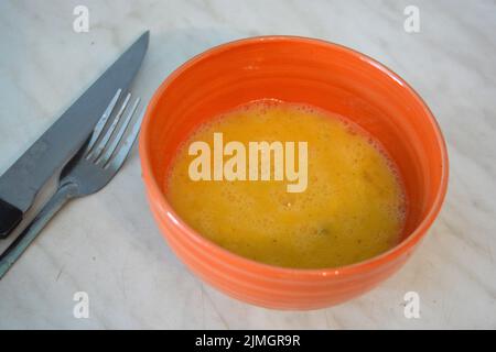 Nourriture saine, œufs brouillés versés dans une assiette d'argile orange. Banque D'Images