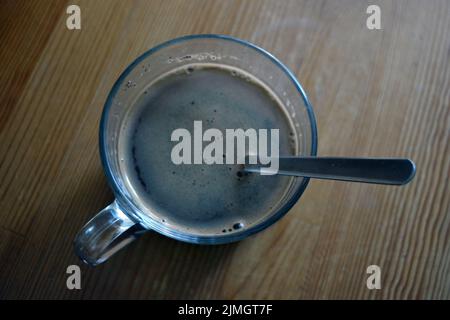 Un délicieux café noir frais est servi dans une tasse en verre et placé sur une table en bois. Banque D'Images