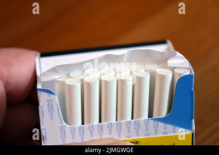 Un paquet de cigarettes blanches fines sur une table en bois jaune. Banque D'Images