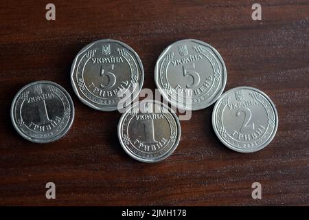 Kopecks ukrainiens, petit changement dans la quantité de un 1, deux 2, cinq 5 hryvnias sont situés sur une table brun foncé. Banque D'Images