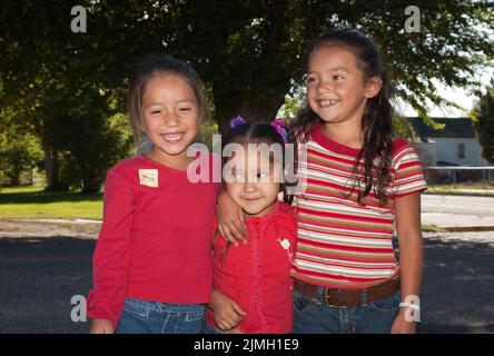 Trois jeunes filles amérindiennes d'âge élémentaire, qui sont des amis et des sœurs, ont mis leurs armes les unes autour des autres et se sont embrasser ensemble. Banque D'Images