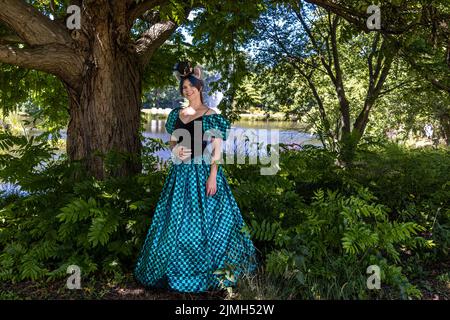 Cottbus, Allemagne. 06th août 2022. Un visiteur du festival d'Elbenwald se tient près d'un étang dans le Spreeauenpark portant un costume du chat Cheshire d'Alice au pays des merveilles. Le festival Elbenwald est un rassemblement de trois jours pour les personnes de tous âges qui aiment les films, la fantaisie, les jeux, les concerts, et toute combinaison de ce qui précède. Credit: Frank Hammerschmidt/dpa/Alay Live News Banque D'Images