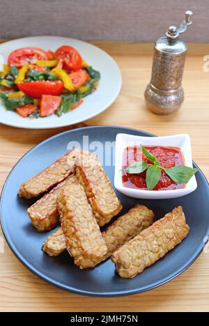 Tempeh poêlé avec sauce marinara maison avec salade de légumes flous en toile de fond Banque D'Images