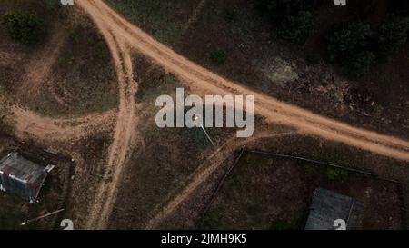 Carrefour de routes rurales non pavées. Au centre de l'intersection se trouve un nid avec des cigognes. Photographie aérienne. Banque D'Images