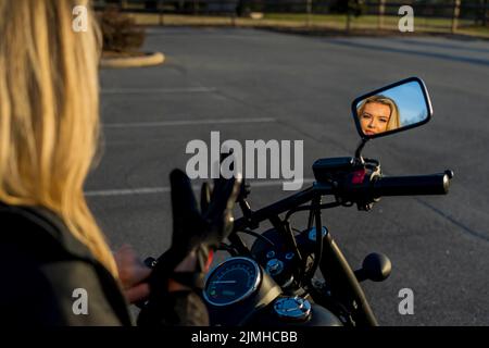 Un beau modèle Blonde apprécie le temps en extérieur en posant avec sa moto Banque D'Images