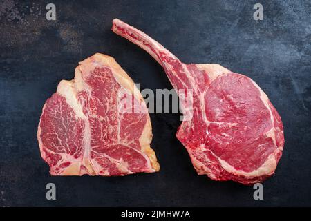 Deux steaks de bœuf harahawk et de porterhouse de wagyu vieilli et sec sont offerts comme vue de dessus sur un panneau rustique avec espace pour les copies Banque D'Images