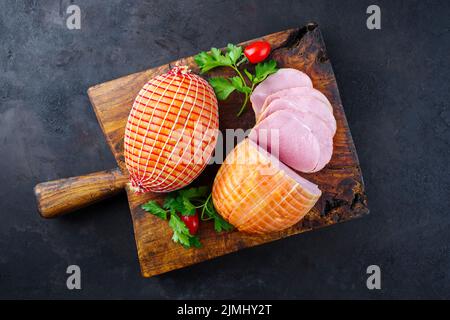 Jambon de Pâques traditionnel à la coque allemande avec tomates et persil offert comme vue de dessus sur un vieux panneau rustique en bois avec espace pour copier Banque D'Images