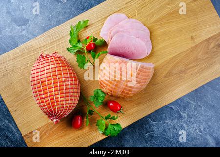 Le jambon de Pâques traditionnel à la coque allemande avec tomates et persil offre une vue de dessus sur une planche en bois moderne avec station santé Copy Banque D'Images