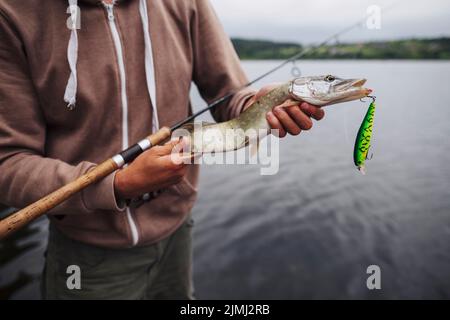 Gros plan sur un homme tenant du poisson fraîchement pêché avec du lure Banque D'Images