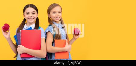 Filles d'école amis. Les élèves heureux avec des livres contiennent des pommes bio vitamine fond jaune, petit déjeuner à l'école. Bannière de l'école fille étudiante Banque D'Images