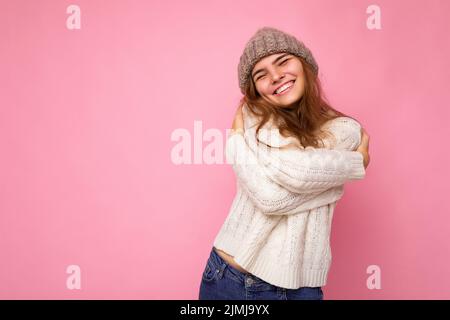 Photo de la belle heureuse positive souriante jeune femme brune isolée sur fond rose mur portant tricoté blanc chandail a Banque D'Images