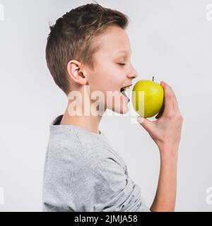 Vue latérale garçon mangeant vert pomme fraîche isolé fond blanc Banque D'Images