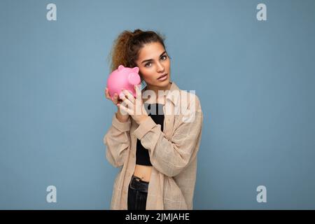 Portrait photo de sincère mignon jeune belle femme attrayante avec des cheveux fclés foncé dans une queue de cheval portant décontracté chemise beige est Banque D'Images