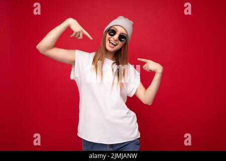Portrait de jeune émotionnel positif heureux joyeux belle femme blonde sombre avec des émotions sincères portant un t-shirt blanc décontracté Banque D'Images