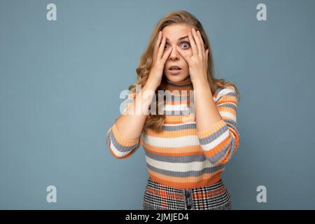 Portrait photo de jeune effrayée belle femme blonde attrayante avec des cheveux ondulés portant l'élégant chandail rayé isolé sur bl Banque D'Images