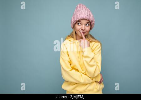 Belle positive heureuse jeune femme blonde isolée sur fond coloré mur portant décontracté élégant vêtements sentiment depuis Banque D'Images