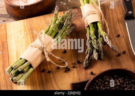 Vue en grand angle des pains d'asperges nouées par du poivre sur une planche à découper en bois Banque D'Images