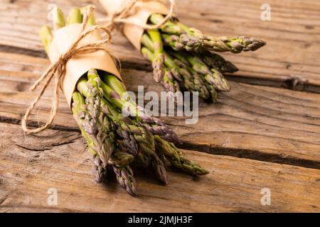 Vue en grand angle des pains d'asperges crus attachés avec des cordes sur une table en bois Banque D'Images