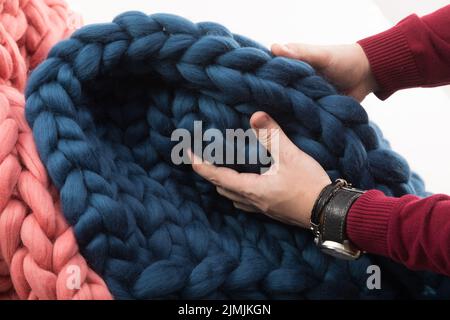 Les mains des hommes touchent une couverture à grosse maille en laine naturelle Banque D'Images