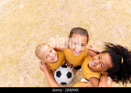 Portrait en grand angle de jeunes filles d'école élémentaire multiraciales souriantes qui se tiennent debout sur le sol Banque D'Images