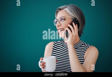 Son temps bien dépensé pour garder vos clients heureux. Une femme d'affaires ayant le café tout en parlant sur son téléphone cellulaire dans son bureau. Banque D'Images