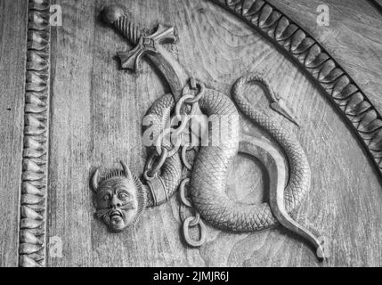 Symbole serpent de diable. Créature magique fantaisie sur une vieille porte, abbaye du 12th siècle en Italie. Banque D'Images